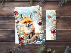 two greeting cards featuring a red fox and pine cones on a wooden background with pine cones