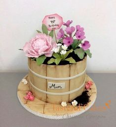 there is a cake made to look like a barrel with flowers in it and writing on the side