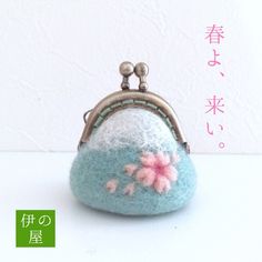 a small purse with flowers on it sitting on top of a white table next to a wall