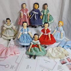 a group of dolls sitting next to each other on top of a sheet of paper