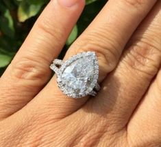 a woman's engagement ring with a pear shaped diamond in the center, on her finger