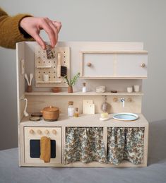 a dollhouse kitchen with sink, stove and cupboards is shown in the foreground