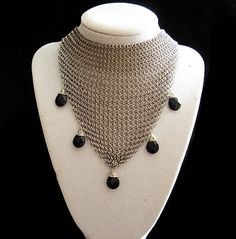 Show off a fashionable look with Collar Mesh Necklace. This sophisticate mesh necklace is pure luxurious elegance. The chain mail feels and behaves like fabric falling softly across the neck and décolleté. It is malleable and ergonomic in the way it drapes over the body's contours. The necklace    Five natural Brazilian Amethyst briolettes adorn this elegant necklace Intricately, intertwined are more then 3000 tiny stainless steel rings form a mesh more widely known as Chainmail is also called c Elegant Black Stainless Steel Chain Necklace, Elegant Chainmail Necklaces For Party, Elegant Chainmail Necklace For Party, Gothic Chain Jewelry For Evenings, Black Stainless Steel Choker, Black Wire Wrapped Choker Jewelry, Handmade Black Stainless Steel Necklace, Black Luxury Metal Chain Necklace, Luxury Black Metal Chain Necklace