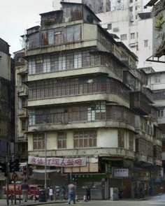 an old building with lots of windows and people walking on the sidewalk in front of it