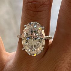 a woman's hand with a large diamond ring on her finger, showing the center stone