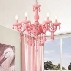 a pink chandelier hanging from the ceiling in a room with curtains and windows