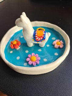 a small white dog figurine sitting on top of a blue plate