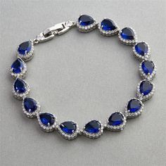 Stunning Sapphire Blue Wedding Bracelet You'll love this exquisite quality Cubic Zirconium bridal statement bracelet. This stunning bridal bracelet bracelet will add a glamorous touch to your wedding day look. It features glistening pear shaped sapphire blue CZ crystals framed with smaller clear cz gems. This bracelet will be a beautiful choice for the bride, mother of the bride or your bridesmaids. Size: about 7 1/2" long, Style: 4562B-SA-7. Color: Silver/Sapphire blue/Clear. Also a stunning br Pear Shape Blue Stone On A Bracelet, Elegant Sapphire Crystal Bracelets, Blue Crystal Bracelets For Formal Occasions, Blue Crystal Bracelet For Formal Occasions, Blue Cubic Zirconia Bracelet With Sparkling Stones, Elegant Blue Crystal Bracelet With Sparkling Stones, Blue Cubic Zirconia Crystal Bracelet, Blue Crystal Bracelets For Anniversary, Blue Cubic Zirconia Bracelet For Party