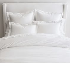 a bed with white sheets and pillows on it