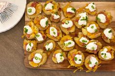 a wooden cutting board topped with mini potatoes covered in cheese