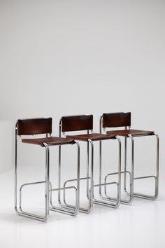 three chairs with wooden seats and metal legs