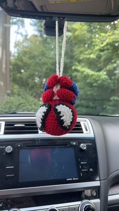 a red, white and blue stuffed animal hanging from the dash board of a car