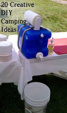 a blue cooler sitting on top of a white table covered in plates and cups next to a bucket