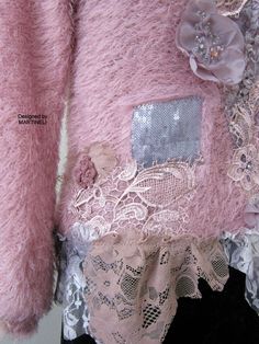 a close up of a pink sweater with lace and flowers on the bottom, as well as an applique