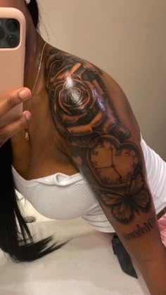 a woman taking a selfie with her cell phone and clock tattoo on her arm