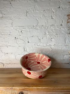 a bowl sitting on top of a wooden table next to a white brick wall,