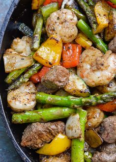 a skillet filled with shrimp, asparagus and peppers