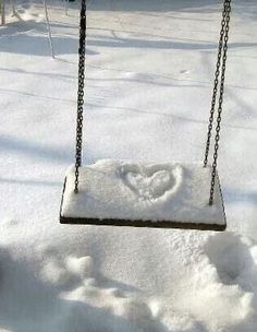 a swing that is in the snow with a heart drawn on it's side