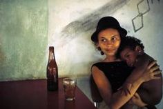 a woman holding a child in her arms next to a beer bottle and glass on a table