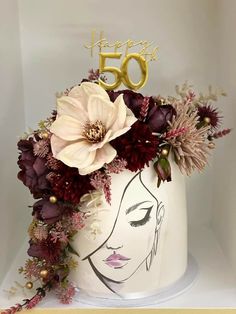 a birthday cake decorated with flowers and gold lettering that says happy 50th on the top