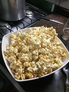 a white bowl filled with popcorn sitting on top of a counter next to a stove