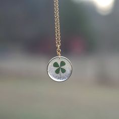 A tiny real pressed four leaf clover is encased in jewelry grade resin within this stunning stardust brass circle bezel. The setting has a textured finish, which gives just a bit of extra dazzle. Attached to a matching chain in the length you choose at checkout. Hangs on a labelled card, easy for gifting! Green Round Jewelry With Birth Flower, Green Birth Flower Round Jewelry, Green Birth Flower Jewelry, Dainty Charm Necklaces With Pressed Flowers, Gold Charm Necklace With Pressed Flowers, Dainty Charm Necklace With Pressed Flowers, Gold Charm Necklaces With Pressed Flowers, Dainty Round Charm Necklaces With Pressed Flowers, Gold Round Charm Necklace With Pressed Flowers