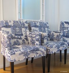 two blue and white chairs sitting next to each other on a hard wood floor in front of a window