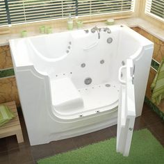 a white bath tub sitting inside of a bathroom next to a green rug on the floor