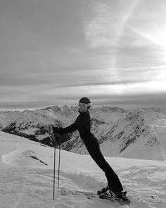 a man riding skis down the side of a snow covered slope with mountains in the background