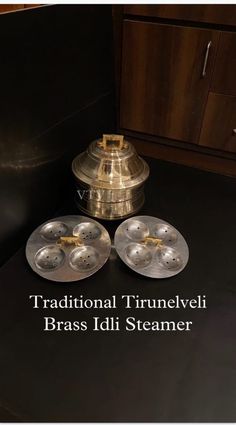 three metal trays sitting on top of a black counter next to a wooden cabinet