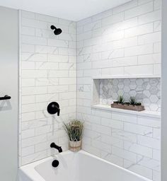 a white bathroom with black fixtures and hexagonal tiles on the walls, along with a plant