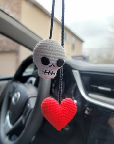 a crocheted skull hanging from the dashboard of a car with a red heart