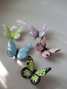 four different colored butterflies sitting on top of a white countertop next to each other