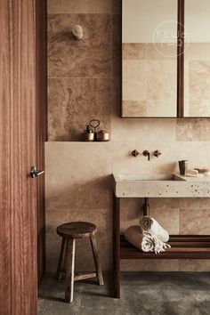 a bathroom with a sink, mirror and stool