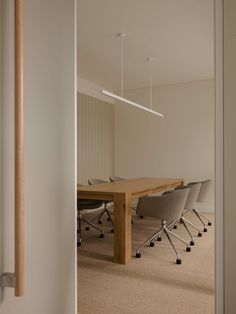 an empty conference room with chairs and a wooden table in the middle, viewed through a doorway