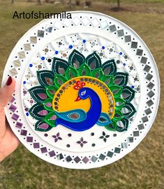 a hand holding a paper plate with a peacock design on the front and back side