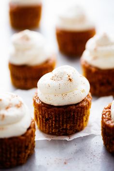 cupcakes with white frosting and cinnamon sprinkles are on a sheet of paper