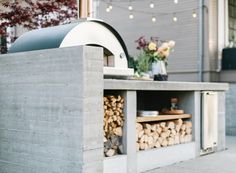 an outdoor bbq with firewood stacked on it