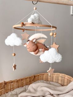 a baby crib with a stuffed animal hanging from it's side and clouds in the background