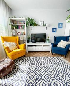 a living room with two chairs and a television in the corner next to a window