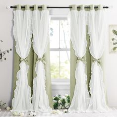 the curtains are hanging on the window sill in front of the windowsill with white flowers and greenery