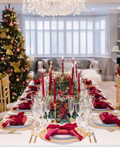 a dining room table set for christmas with red napkins and place settings on it