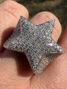 a close up of a person's hand holding a ring with a star on it