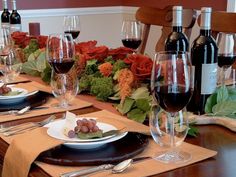 the table is set with wine glasses, plates and silverware