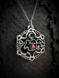 The Clauneck Seal Pendant with Gothic Ornaments is a handcrafted piece made from fine pewter, containing 98% tin, featuring an intricate design that showcases the Seal of Clauneck adorned with elegant gothic embellishments. This pendant measures 3 cm in diameter and is enhanced with a gemstone of your choice, allowing for personalization and individual expression. It comes with a choice of a stainless steel chain in either 18 or 24 inches, ensuring durability and hypoallergenic properties. The S Gothic Metal Jewelry With Antique Finish, Symbolic Metal Necklaces With Antique Finish, Symbolic Pewter Jewelry For Collectors, Spiritual Engraved Pewter Jewelry, Symbolic Antique Silver Nickel-free Jewelry, Gothic Silver Necklaces With Antique Finish, Silver Gothic Necklaces With Antique Finish, Silver Gothic Necklace With Antique Finish, Symbolic Sterling Silver Jewelry With Antique Finish