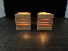 two lit candles sitting on top of a wooden block