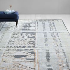 a blue couch sitting on top of a white floor next to a rug covered in patterns