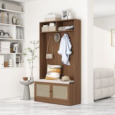 a white living room with a wooden bench and storage unit filled with towels, pillows and other items