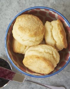 three biscuits in a bowl next to a spoon