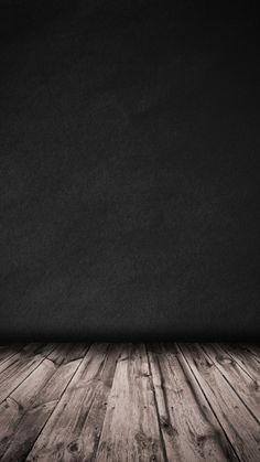 an empty room with wooden floors and black walls